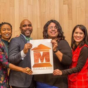 Group photo of individuals holding up a Museum Hue logo sign