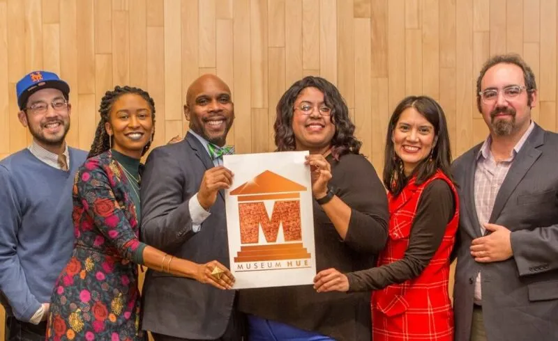 Group photo of individuals holding up a Museum Hue logo sign