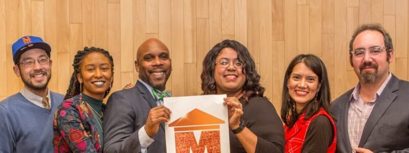 Group photo of individuals holding up a Museum Hue logo sign
